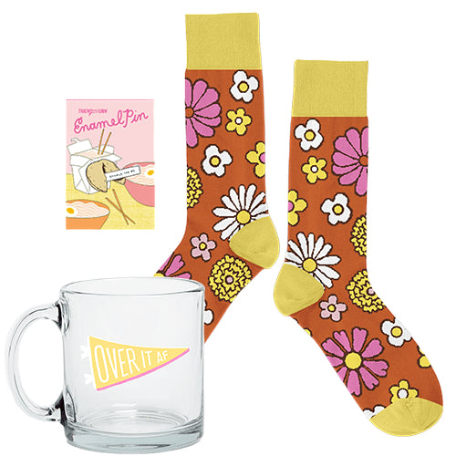 Over It Mug Kit with a colorful glass mug, cozy patterned socks, and a small enamel pin.

