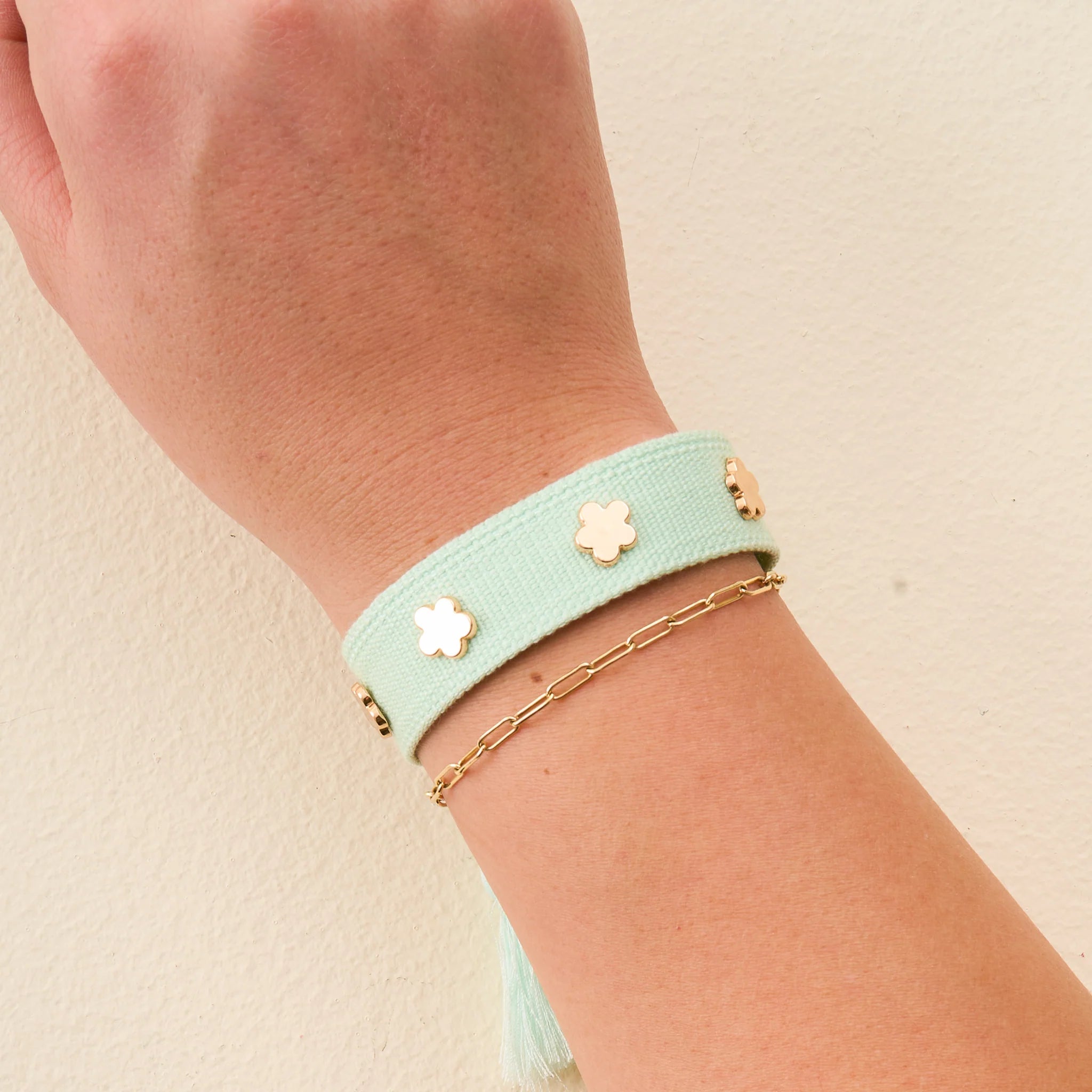 Aqua adjustable woven bracelet with gold flower charms and tassel ends