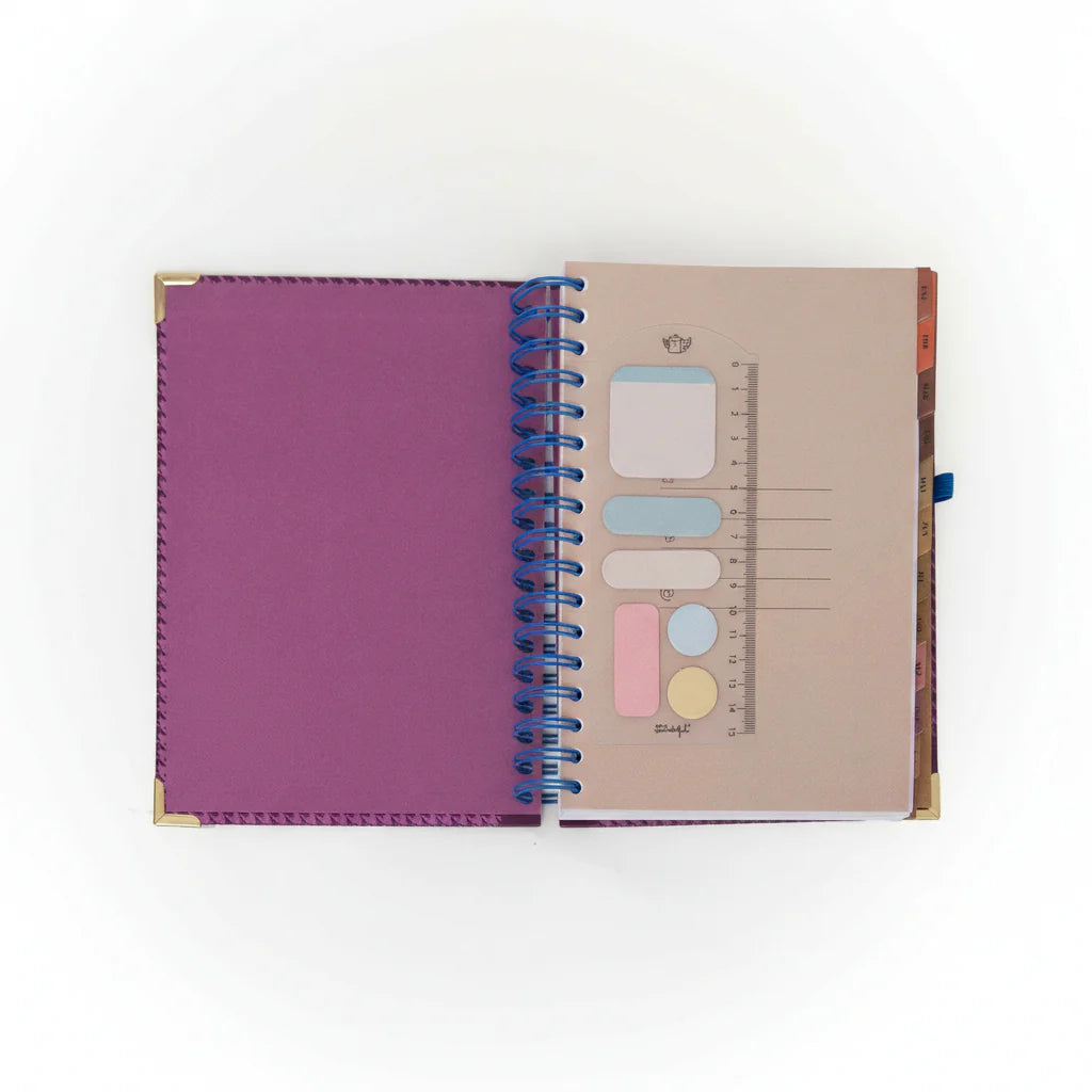 La Vida Es Hoy 2026 daily planner with purple cover, blue elastic band, and matching pen from Funky Confetti