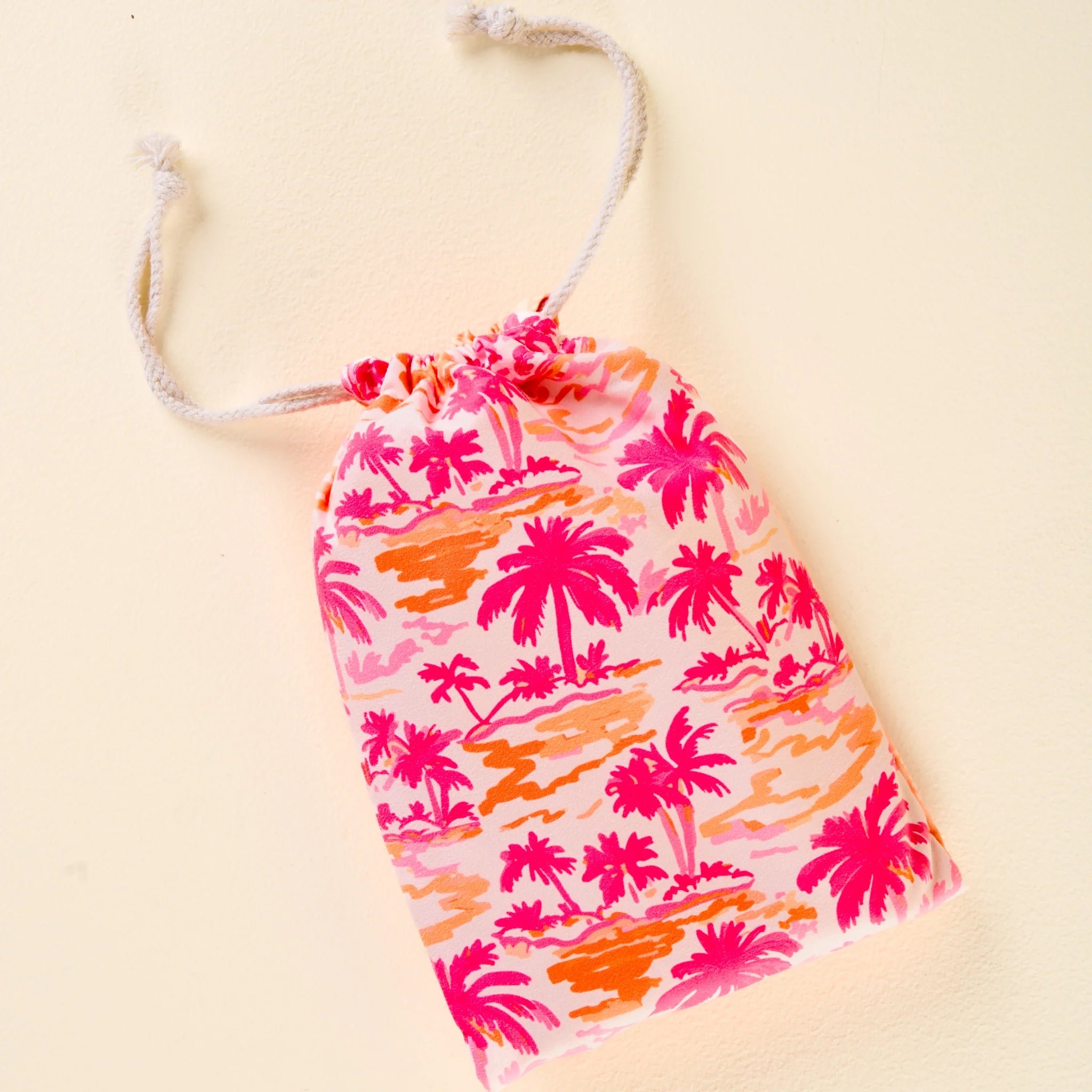 Tropical palm print XL quick-dry microfiber beach towel in pink and orange with matching drawstring bag from Funky Confetti